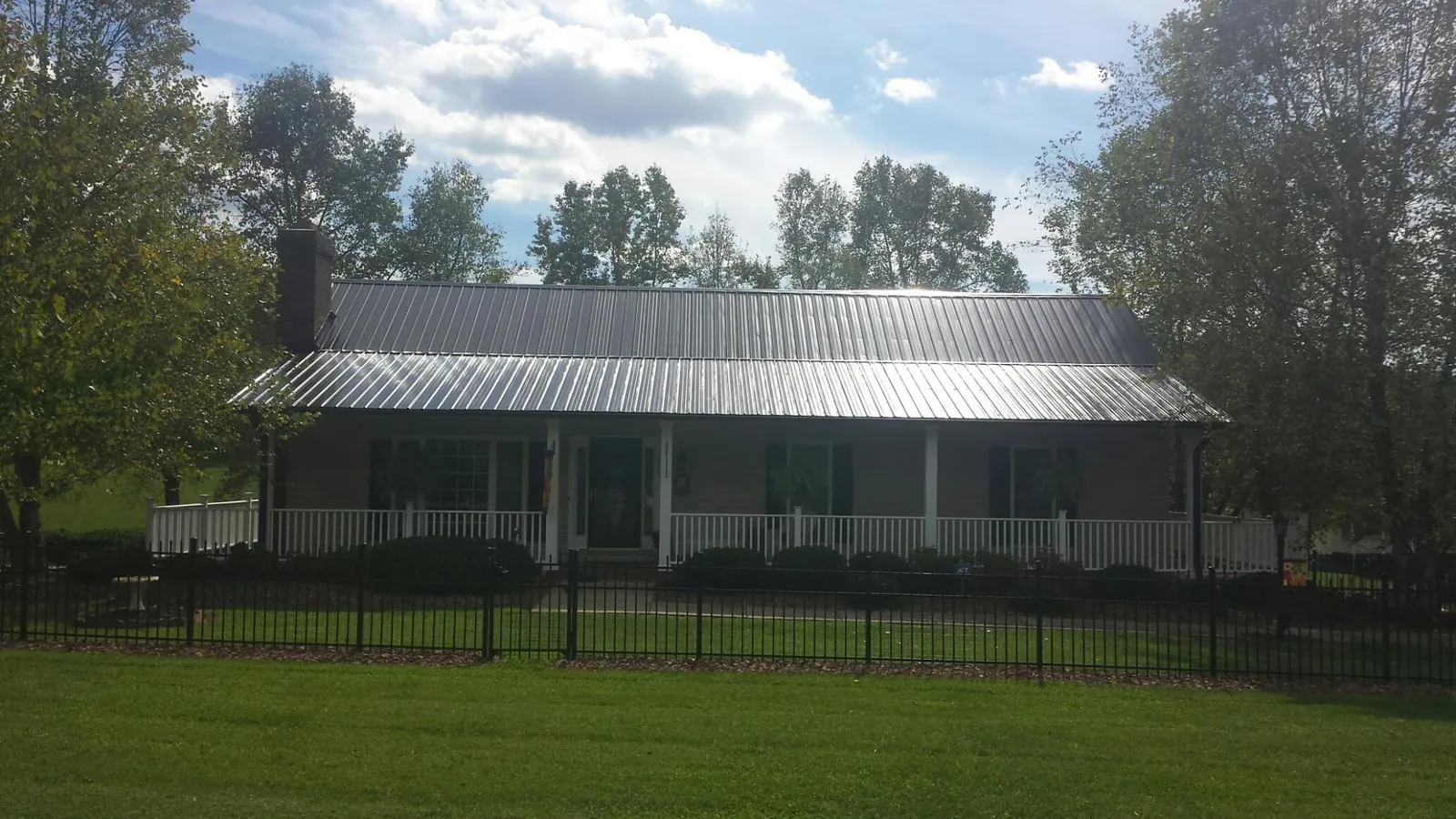 Gray metal roof on a brick ranch with a full width front porch — Gutter Guard Installation work by our crew in Lyman