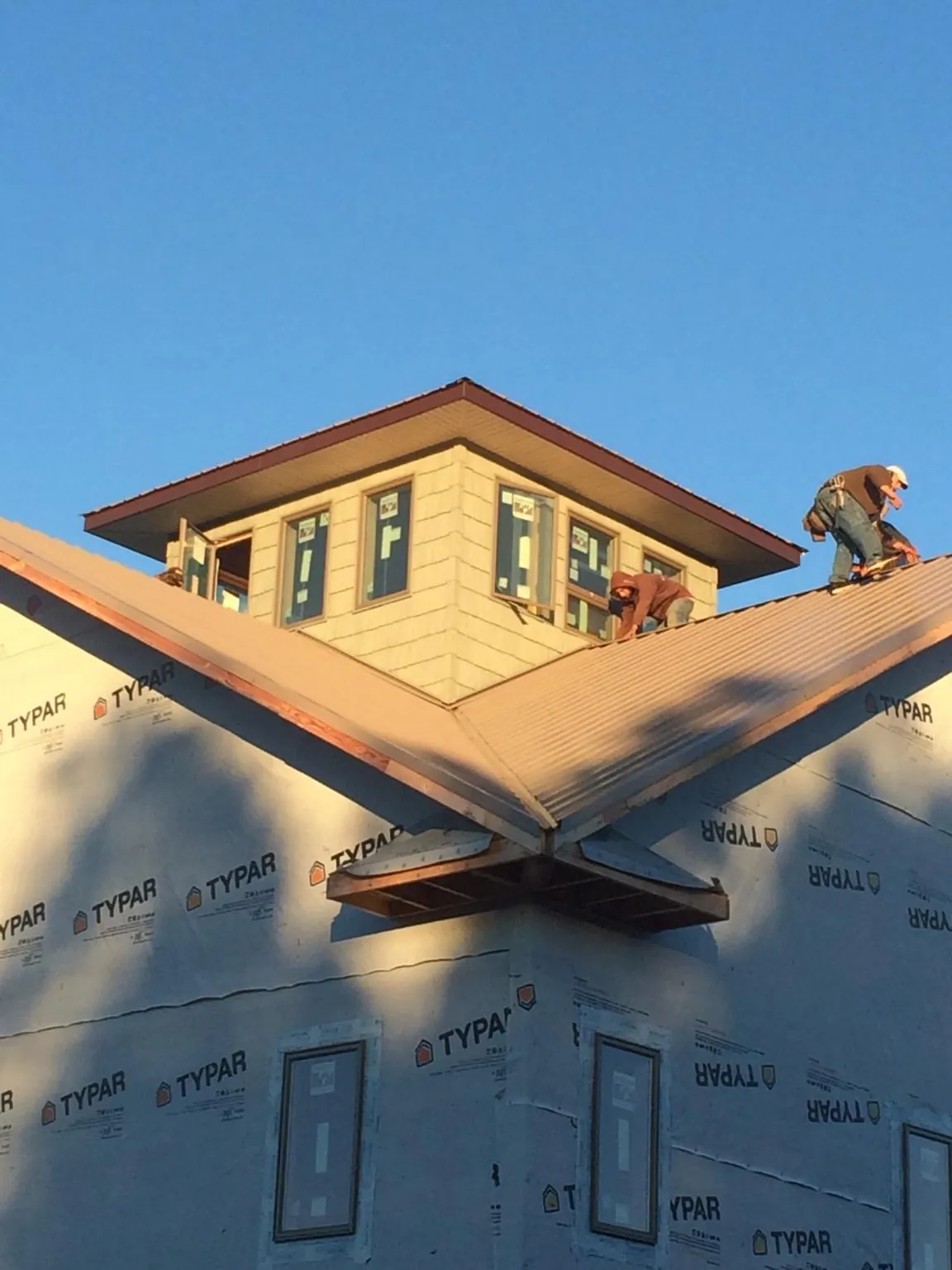 Roofers working around a rooftop cupola on a new metal roof at sunset — Roof Waterproofing in Lyman by Roofing Brothers